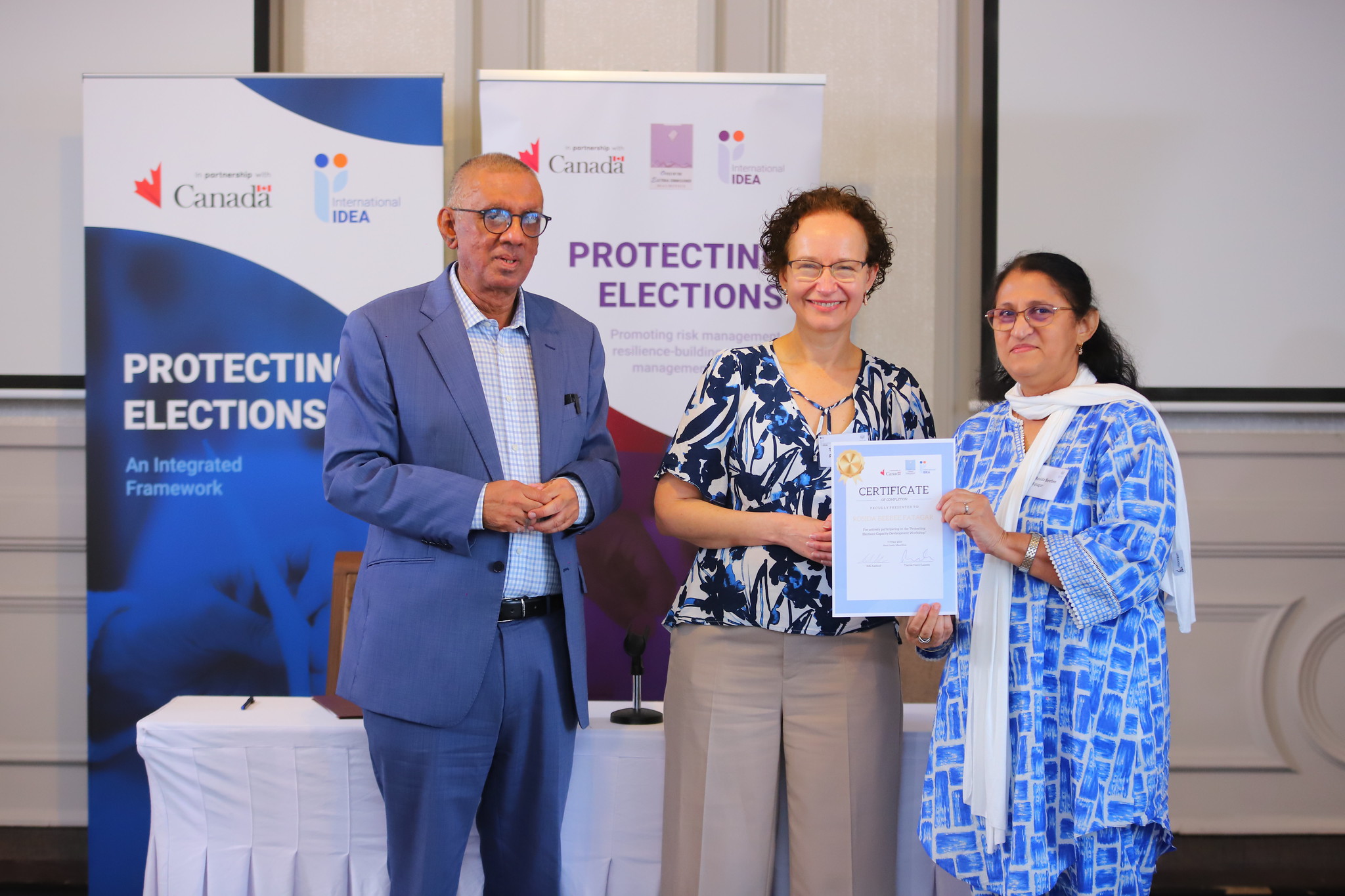 Commissioner Irfan Abdool Rahman (left), Office of the Electoral Commissioner of Mauritius, and International IDEA’s Head of Electoral Processes, Therese Pearce-Laanela (centre), present a certificate to a participant during a workshop funded by Canada on developing capacity to protect elections, held in Mauritius in May 2024. Credit: Lume Production Company Ltd